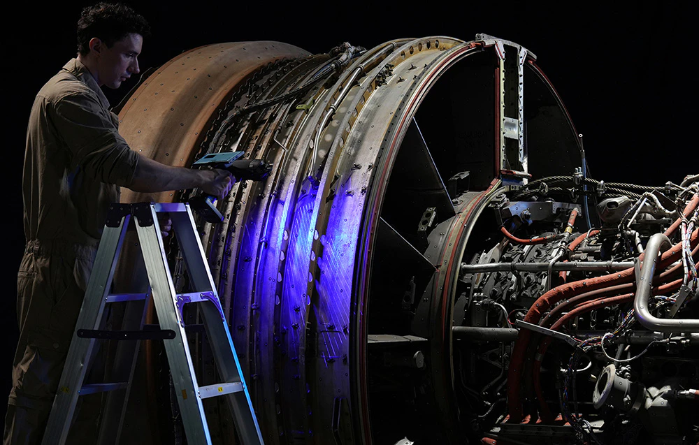 Un tehnician scanează o turbină mare de avion cu un scaner 3D.