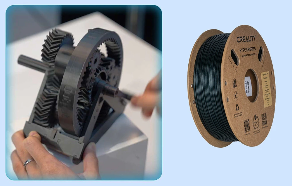 Mâini care țin un model de angrenaj negru lângă o bobină de filament Creality Hyper Series