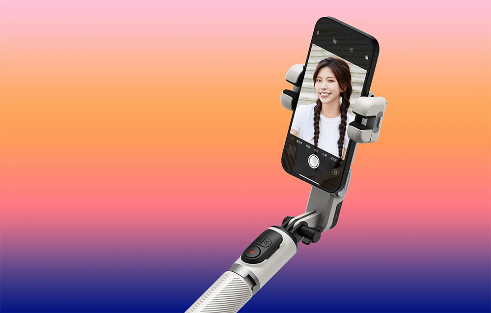 Un gimbal pe un braț extensibil cu un smartphone care afișează o selfie a unei femei zâmbitoare pe un fundal portocaliu.