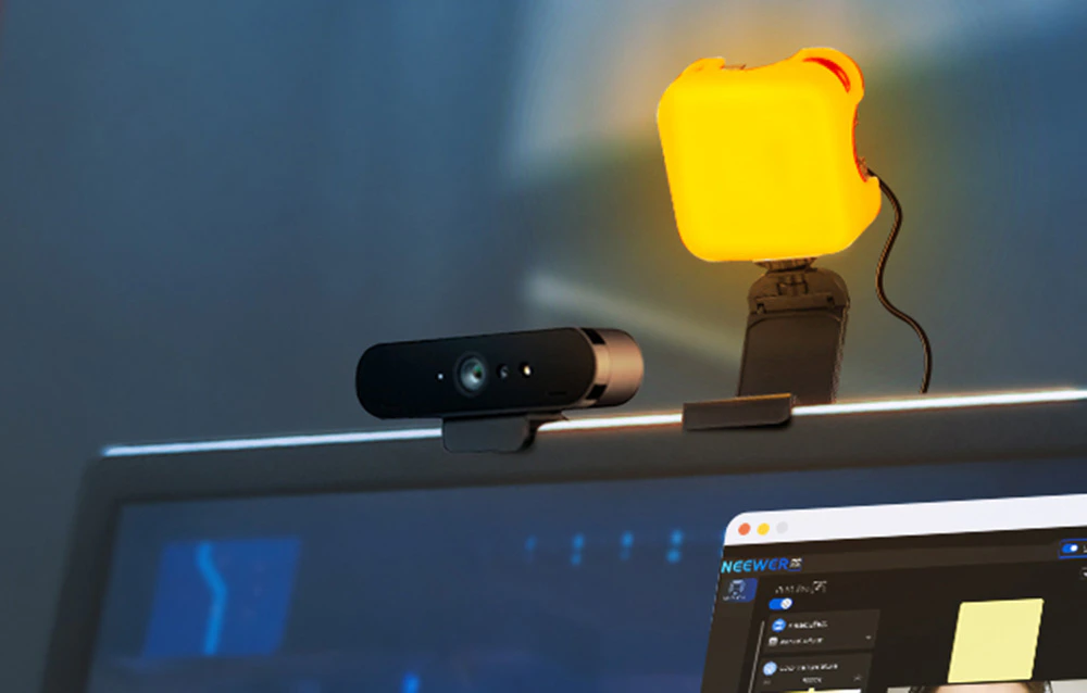 Lampă LED portocalie și cameră web montată deasupra monitorului unui computer cu software-ul Neewer pornit