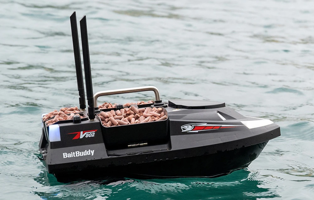 BaitBuddy V602 RC bait boat cu pelete roz plutind pe apă limpede turcoaz