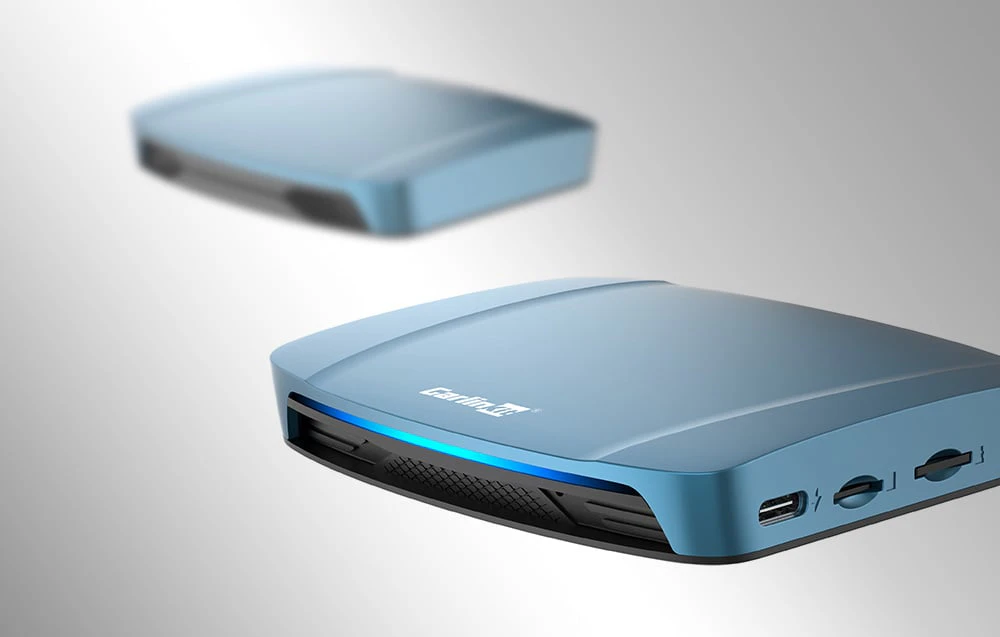Două adaptoare wireless Carlinkit TBOX ULTRA, pe un fundal deschis, unul estompat.