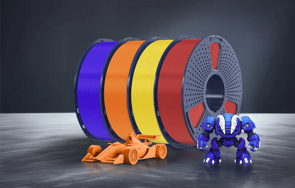 Patru bobine cu filament albastru, portocaliu, galben și roșu lângă o mașină portocalie și un robot albastru.