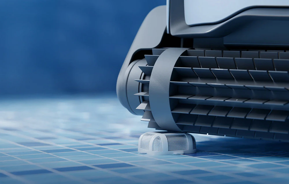 Prim-plan al șenilei unui robot pentru piscină, cu o perie de curățare vizibilă care se deplasează peste gresia albastră