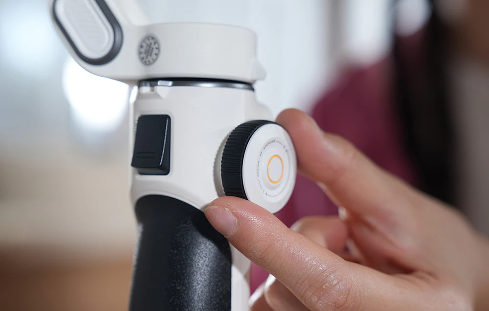 Prim-plan al butonului de control de pe un gimbal ținut în mână.