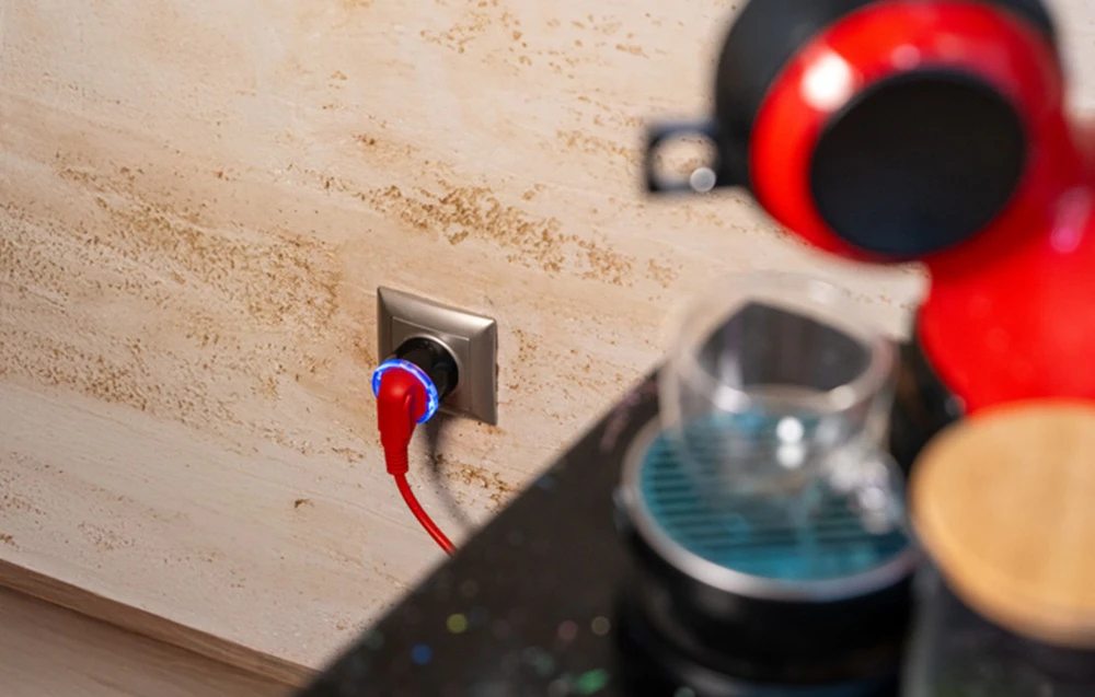 Cafetieră lângă Shelly Plug S cu lumină de fundal albastră și fir roșu