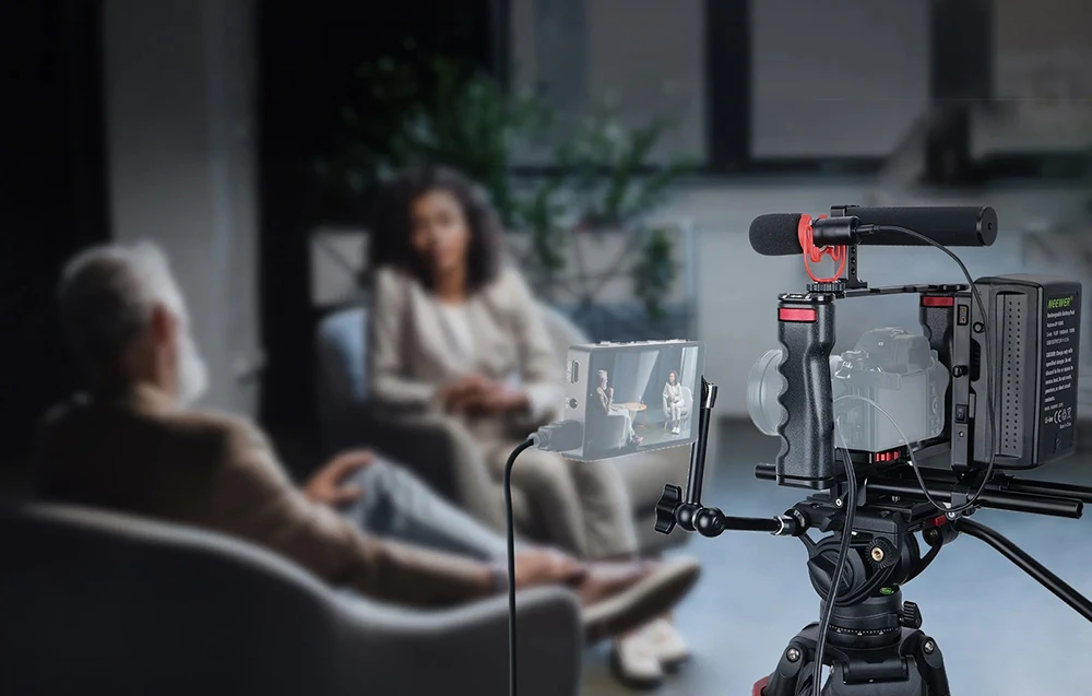 Configurație de filmare cu cameră, microfon și monitor montate pe un trepied profesional în timpul unui interviu