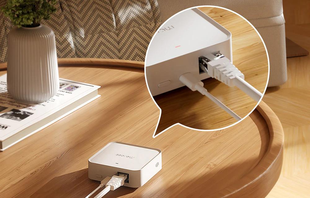Un mic hub de rețea este așezat pe o masă, un prim plan arată cablurile Ethernet și de alimentare conectate