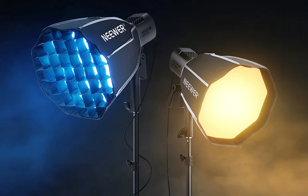 Două lumini Neewer cu softbox-uri: una cu grilă atașată emite lumină albastră, cealaltă fără grilă emite lumină galbenă.