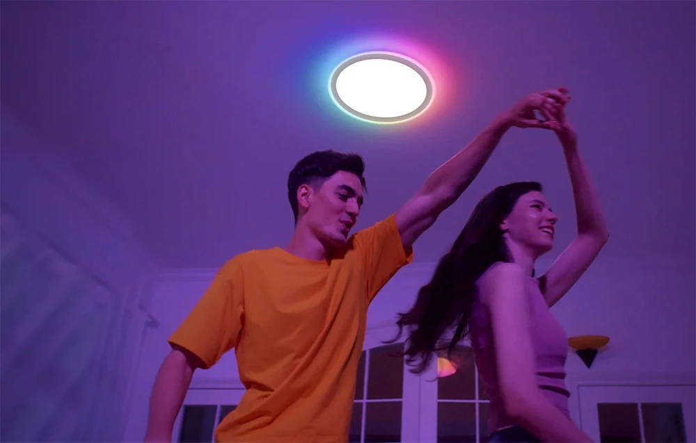 Cuplu dansând într-o cameră iluminată de lampa Yeelight Mars C300 care emite lumină multicoloră.