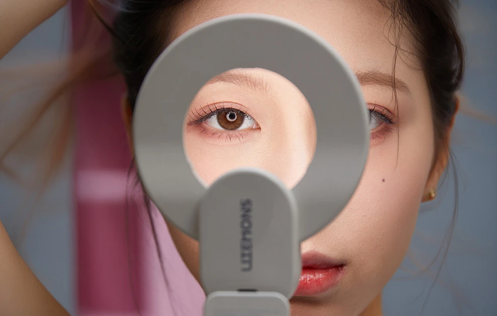 Prim-plan al ochiului unei femei, văzut prin centrul unui inel luminos circular pentru selfie, oprit