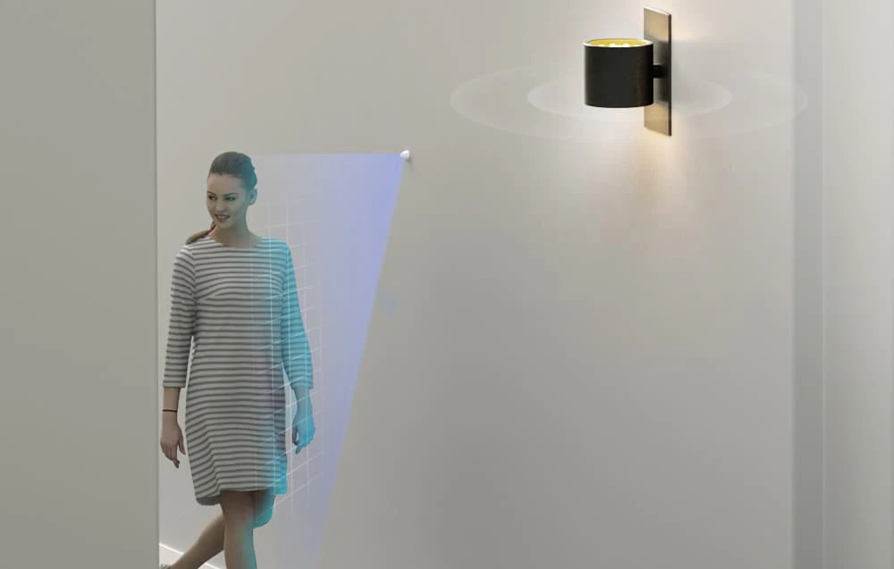O femeie merge pe hol; lampa se aprinde când se detectează mișcare