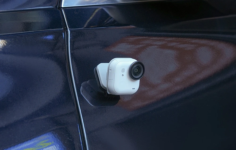 Camera de pe suport este fixată magnetic pe partea laterală a unei mașini de culoare închisă.