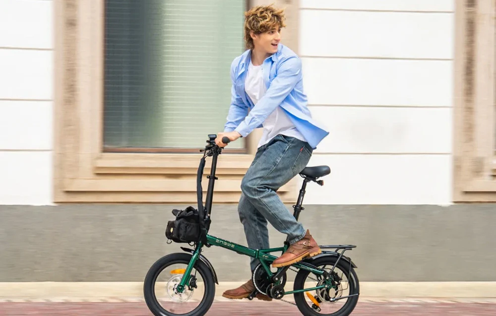Un bărbat merge pe o bicicletă electrică pliabilă verde pe o stradă din oraș