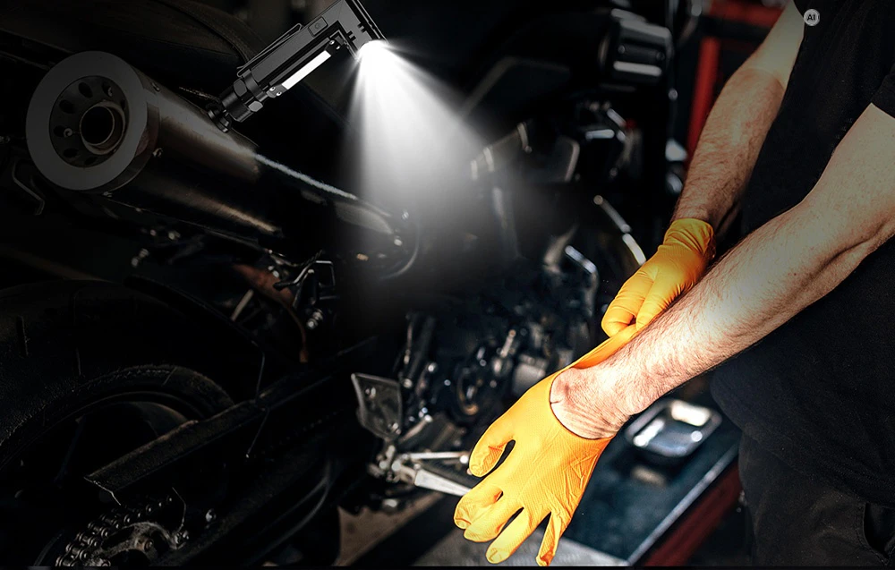 Un mecanic care poartă mănuși galbene și lucrează la o motocicletă iluminată de o lanternă Superfire