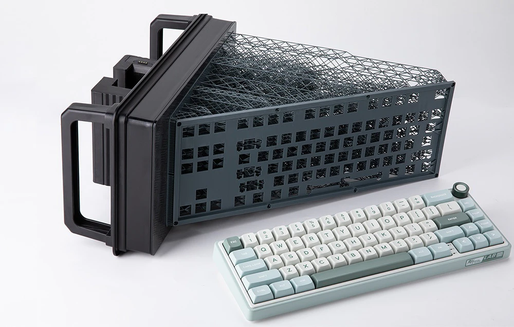 O carcasă de tastatură gri, imprimată 3D, cu un model ajurat, se află lângă o tastatură finisată, de culoare verde mentă