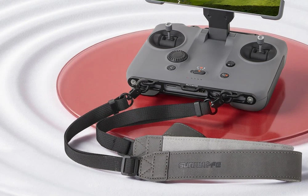 Controler dronă cu ecran montat și șnur atașat pe masă roșie