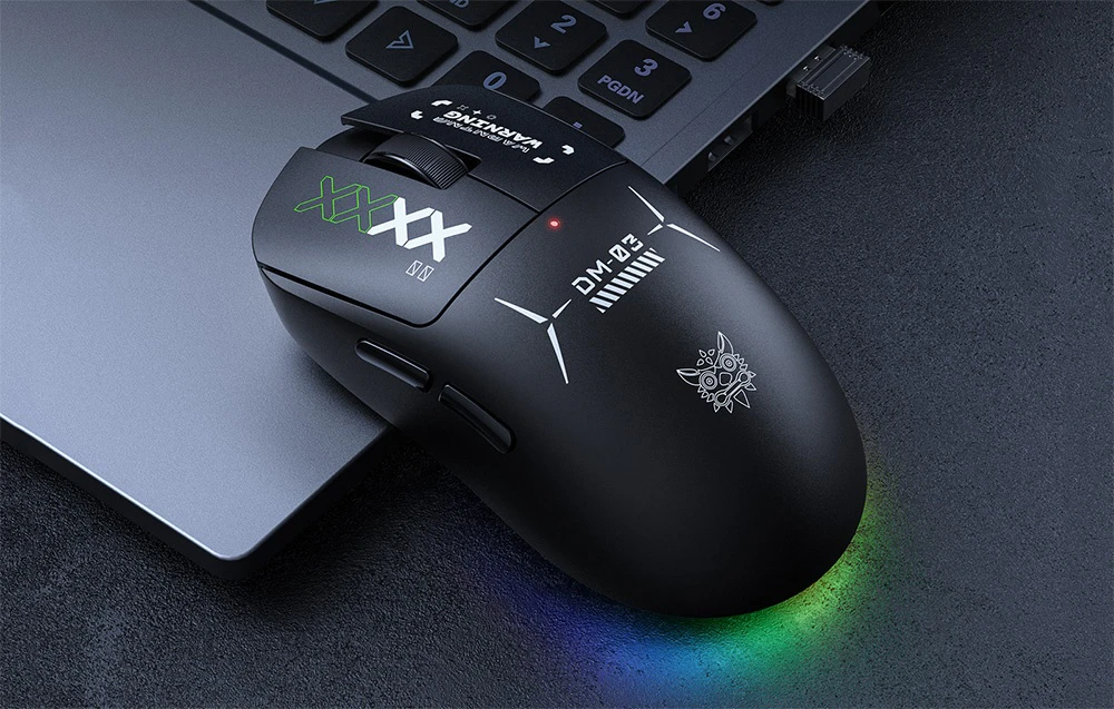 Mouse de computer Onikuma negru așezat lângă un laptop