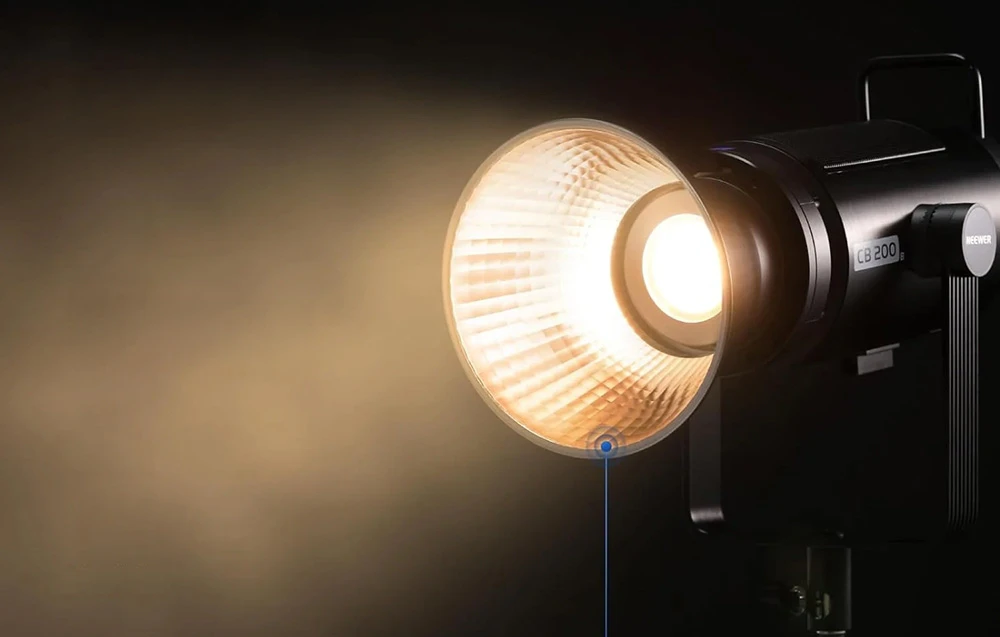 Lampa profesională de studio aprinsă, emițând o lumină puternică și caldă cu un reflector montat.
