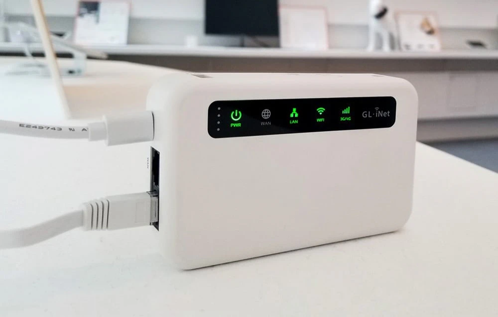 Un router alb așezat pe o masă, cu un cablu de alimentare USB și un cablu Ethernet alb conectate.
