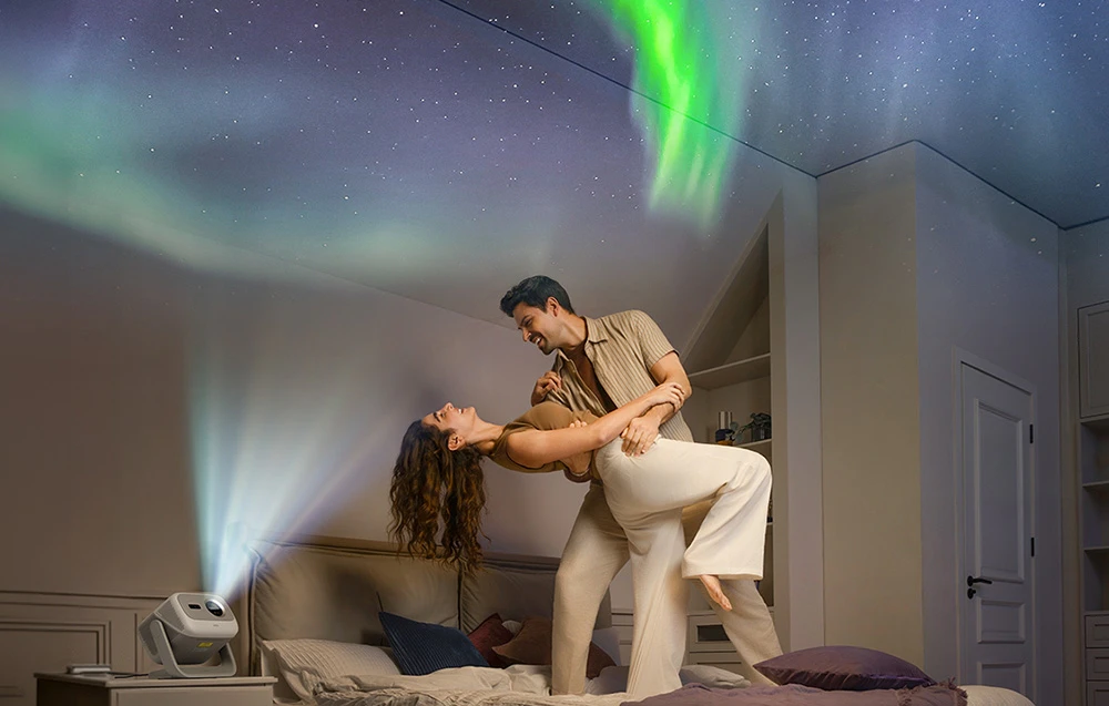 Un cuplu dansează în dormitor, iar proiectorul afișează pe tavan o imagine a cerului nocturn cu aurora boreală
