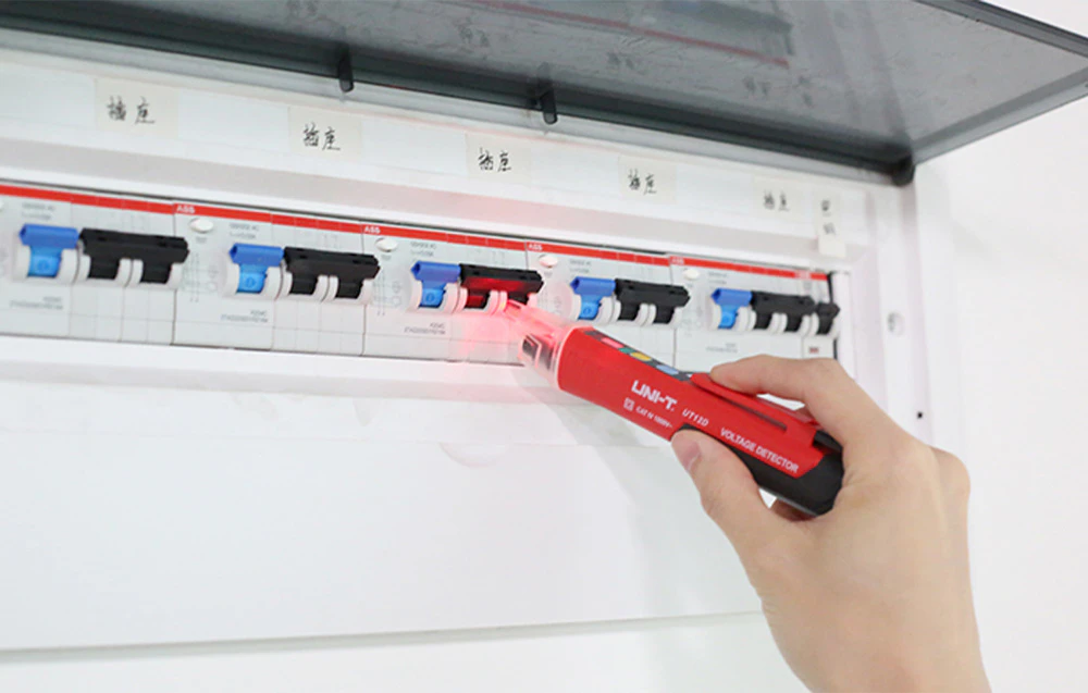 The Hand utilizează un detector de tensiune fără contact pentru a testa întrerupătoarele din tabloul electric.