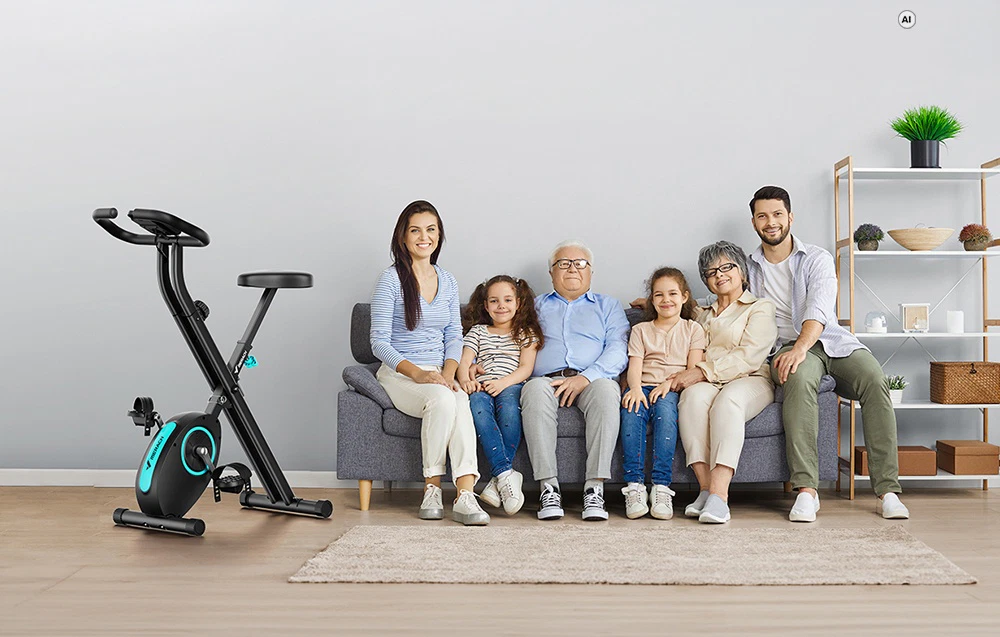 O familie multigenerațională stă pe canapeaua din sufragerie; lângă ei se află o bicicletă staționară Merach neagră