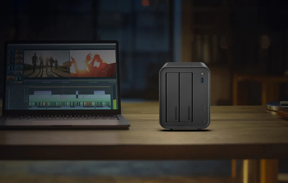 Carcasa NAS se află pe un birou lângă un laptop pe care rulează un program de editare video