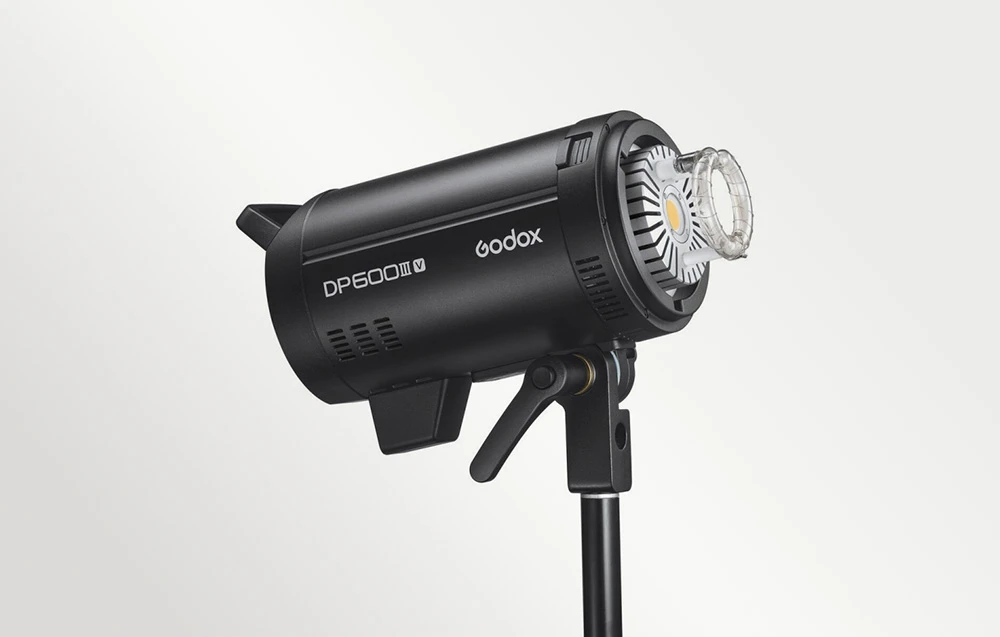 Unitatea de bliț Godox DP600III-V pe un trepied, vedere frontală care arată capul de bliț și lumina de modelare rotundă cu LED