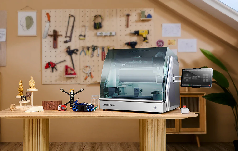 Routerul CNC Carver se află pe o masă într-un atelier luminos, lângă modelele finite