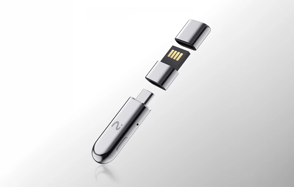 Trei părți metalice separate ale dongle-ului, cu un simbol în formă de undă și contacte aurii, plutesc deasupra unei suprafețe de culoare deschisă.