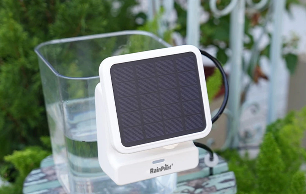 Panou solar RainPoint amplasat lângă un recipient cu apă pe balcon sau în grădină