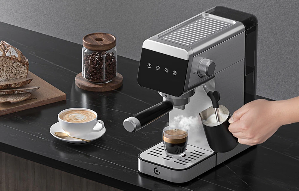 O persoană spumează lapte cu duza de abur a unei mașini de espresso lângă o ceașcă de cafea