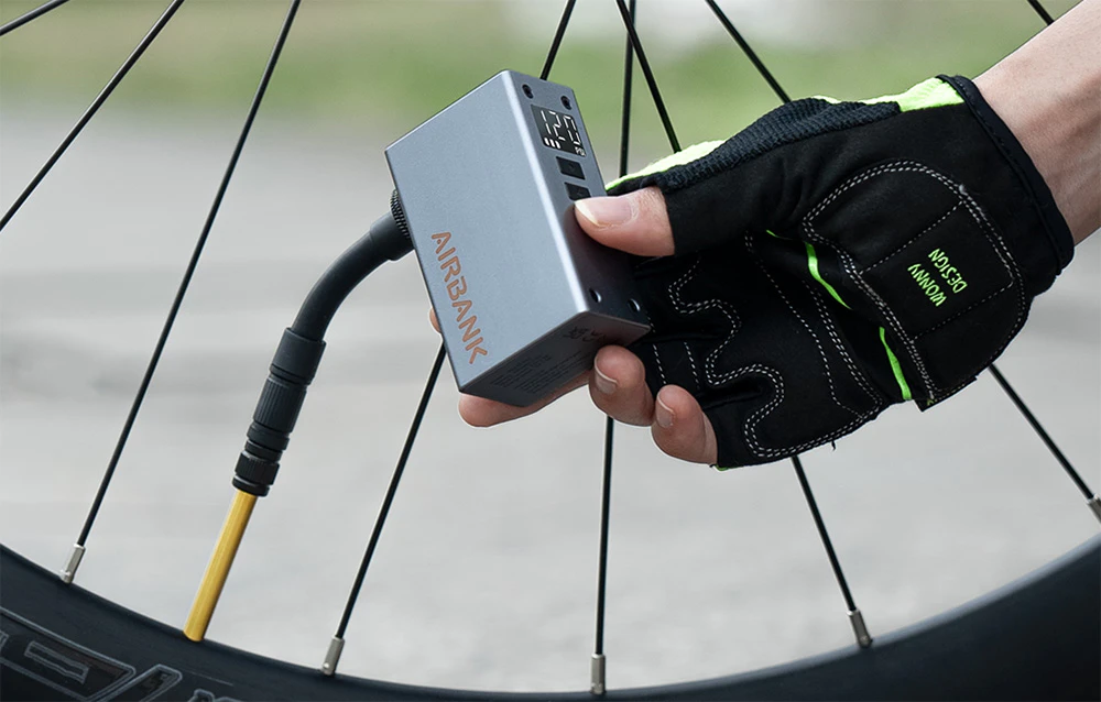 Pompa conectată printr-un furtun flexibil la o supapă de roată de bicicletă în timp ce umflă un pneu.