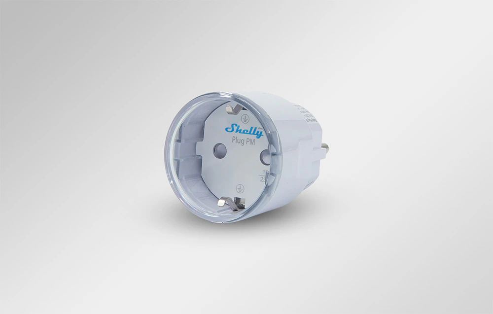 Detaliu al prizei inteligente Shelly Plug PM în culoare albă, cu logo-ul producătorului și împământare Schuko vizibilă.