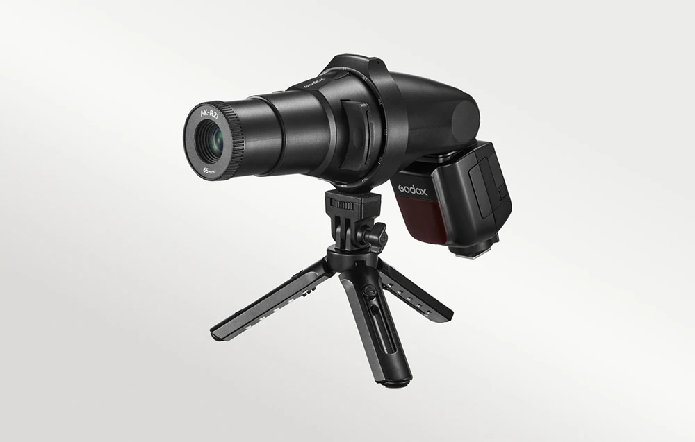 Accesoriu de proiecție Godox AK-R21 cu un bliț, montat pe un mic trepied de masă negru
