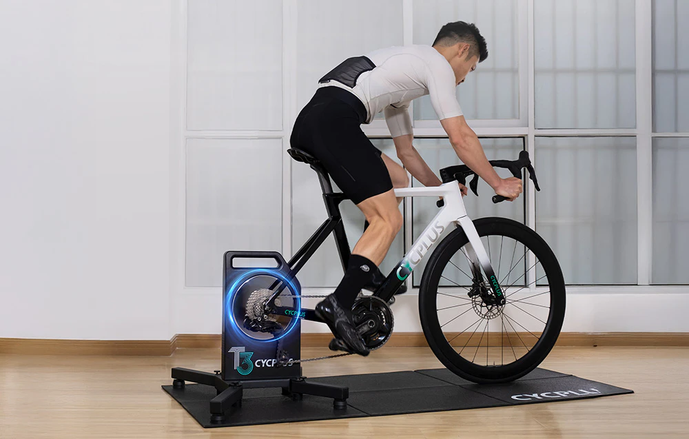 Un bărbat se antrenează pe o bicicletă cu iluminare albastră pe trainerul Cycplus T3
