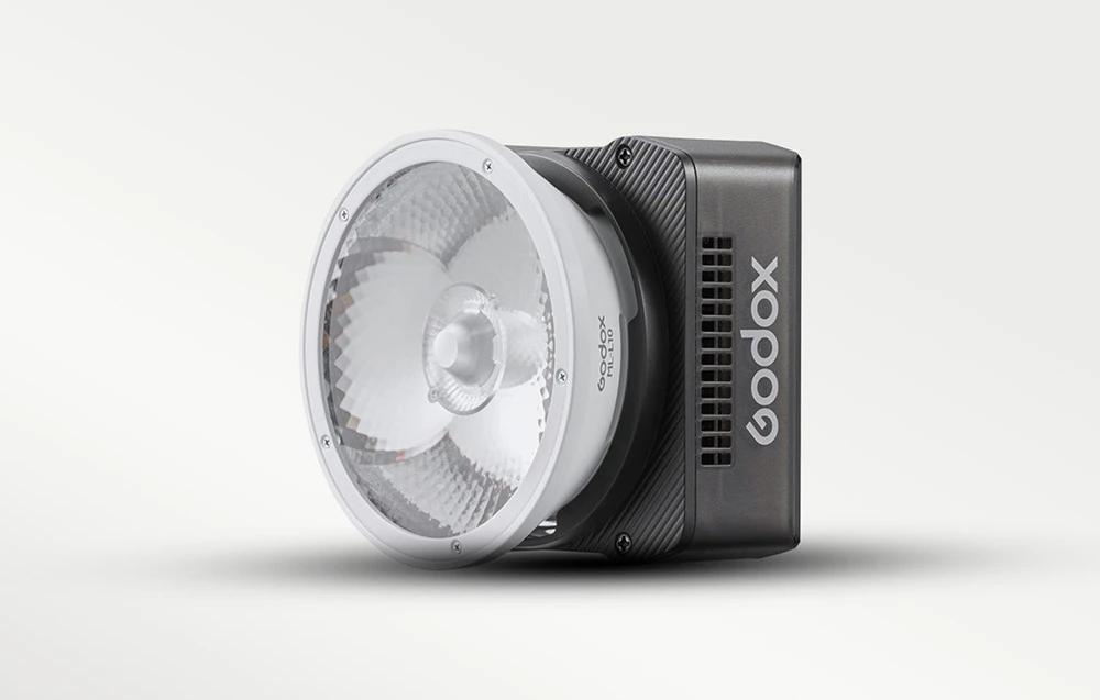 O lampă LED Godox cu o lentilă de colimare albă, prezentată pe un fundal luminos și uniform