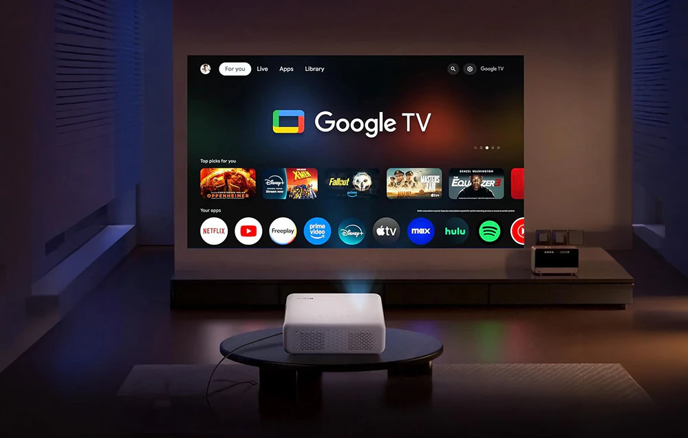 Proiector care afișează interfața Google TV pe peretele din sufragerie.