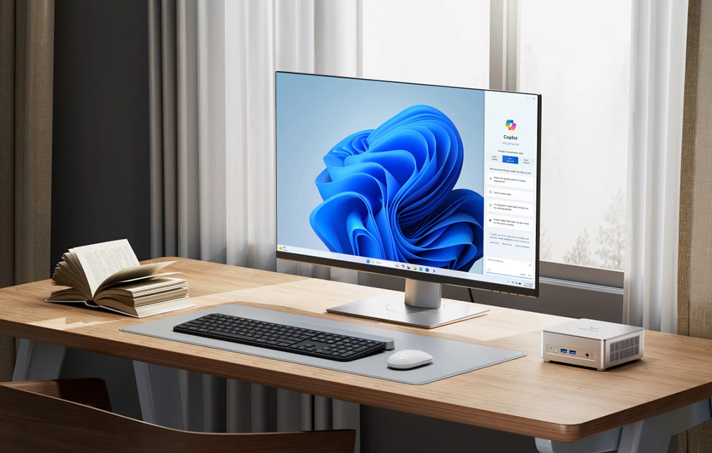 pe birou se află un mini PC, un monitor, o tastatură, un mouse și o carte