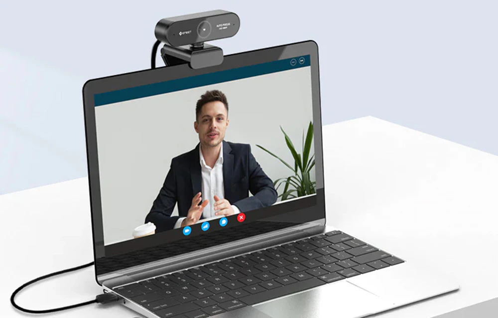 O cameră web montată pe marginea superioară a unui laptop deschis pe un birou alb.