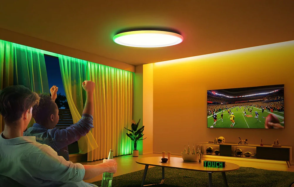 Doi bărbați urmărind un meci în camera de zi luminată de lampa Yeelight Mars C400 în culorile verde și galben.