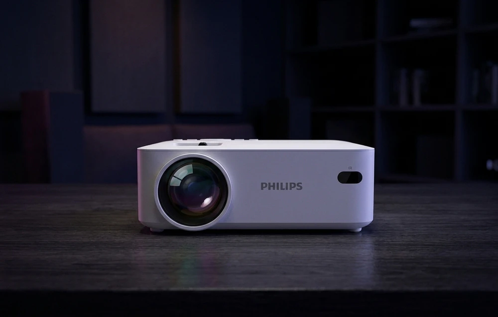 Un proiector PHILIPS alb așezat cu fața spre înainte pe o masă din lemn de culoare închisă într-o cameră slab iluminată