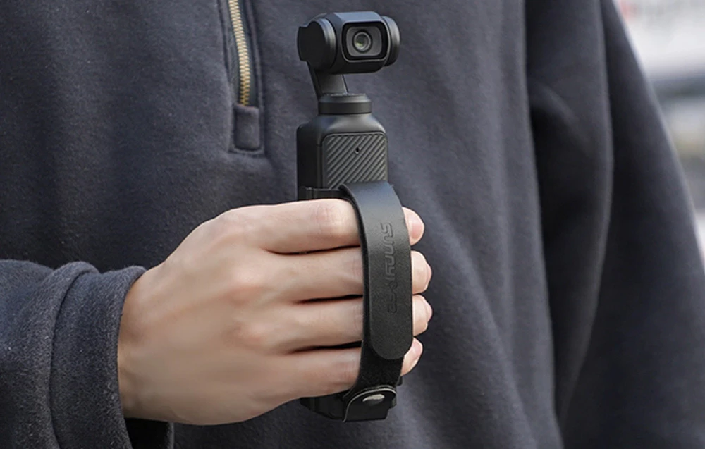 Bărbat filmând cu camera DJI OSMO Pocket 3, pe care o ține cu ajutorul suportului de palmă Sunnylife.