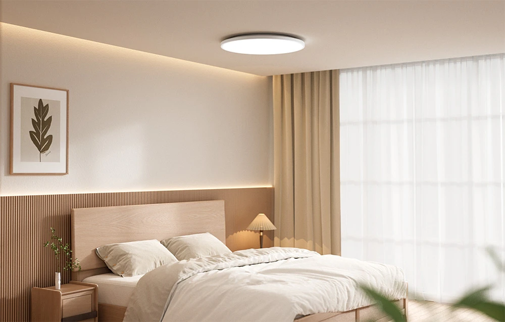 Dormitor luminos cu pat și plafonieră Yeelight Mercury C300 aprinsă.