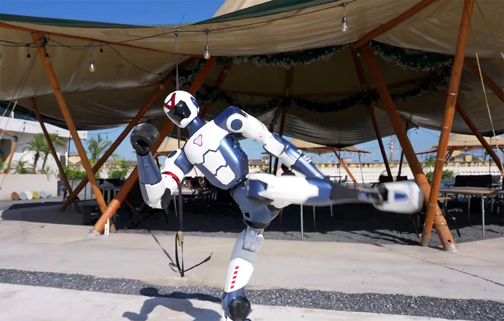 Un robot umanoid executând o lovitură înaltă de karate sub un cort mare de grădină