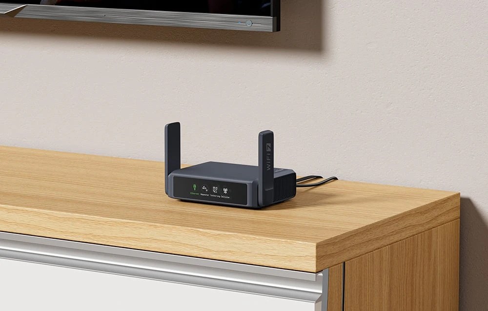 Un router de culoare închisă, cu antene, se află pe o comodă de culoare deschisă, sub televizor