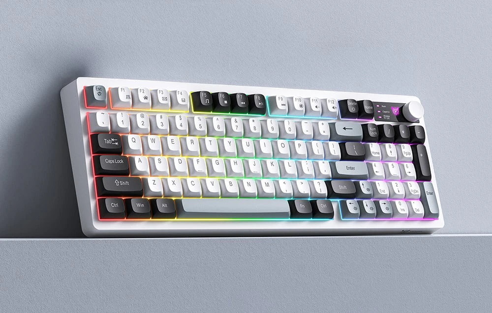 O tastatură alb-negru cu iluminare colorată pe un suport gri, pe fundalul unui perete gri