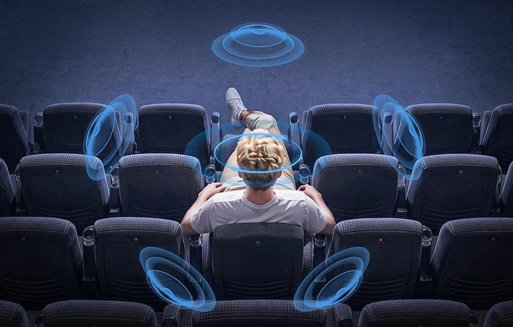 O persoană așezată într-o sală de cinema, înconjurată de o reprezentare grafică a sunetului surround