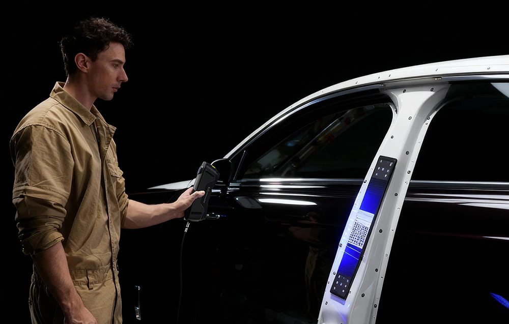 Un tehnician folosește un scaner 3D pentru a digitaliza ușa unui vehicul.